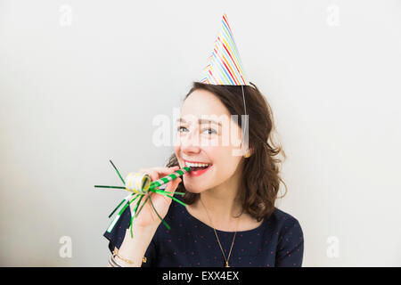 Smiling young woman with party horn blower Stock Photo