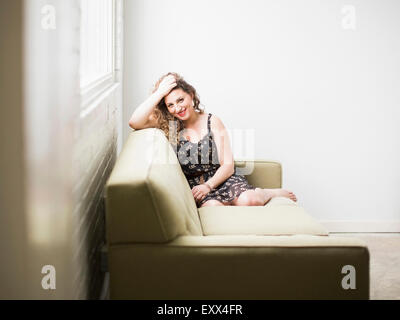 Smiling woman sitting on sofa Stock Photo