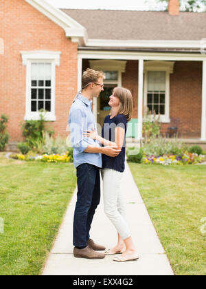 Young couple standing on footpath in front of house Stock Photo