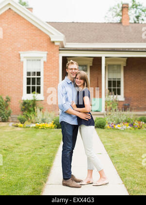 Young couple standing on footpath in front of house Stock Photo