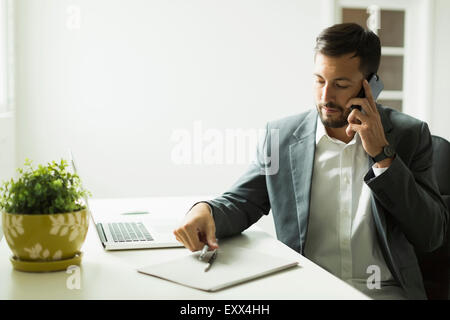 Young man sitting at desk and looking at laptop Stock Photo