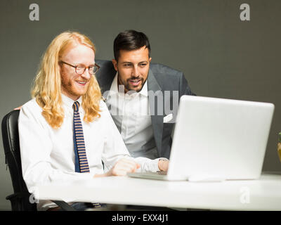 Businessmen looking at laptop in office Stock Photo