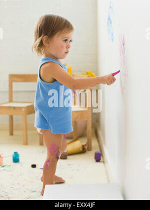 Girl (2-3) painting on wall Stock Photo