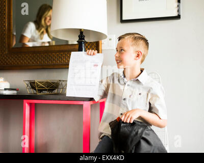 Smiling boy (6-7) showing schoolpaper Stock Photo