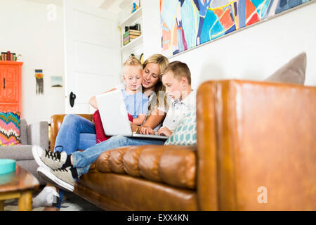 Mother with children (4-5, 6-7) using laptop on sofa Stock Photo
