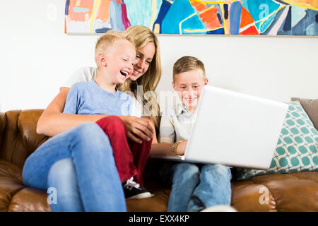 Mother with children (4-5, 6-7) using laptop on sofa Stock Photo