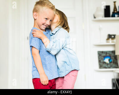 Little girl (4-5) whispering into brother's (4-5) ear Stock Photo