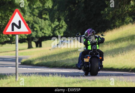 A motorcyclist approaches a bend in a countryside road in Derbyshire England UK Stock Photo