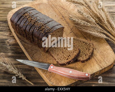 Sliced black bread on the old wooden plank. Stock Photo