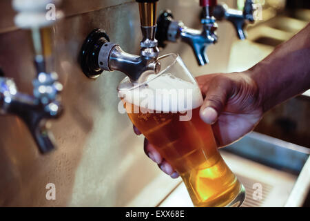 African American bartender filling beer glass from a bar tap Stock Photo