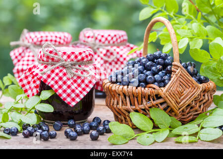 Basket with blueberries and three jars of jam. Stock Photo