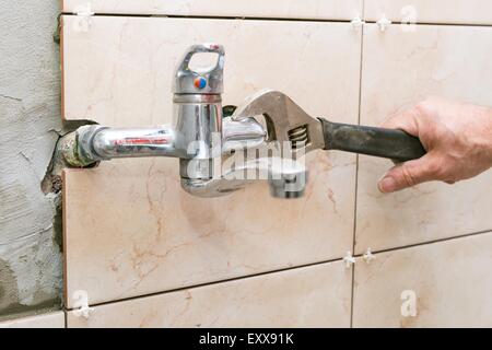 Plumber hands fixing water tap with spanner Stock Photo