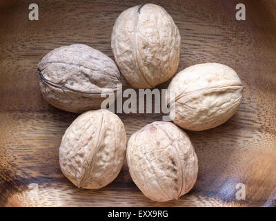 five ripe walnuts on wooden background Stock Photo