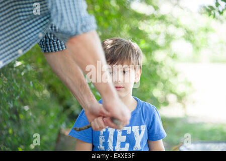 Boy watching father break stick Stock Photo