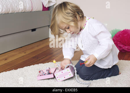 Little girl removing necklace from jewellery box Stock Photo