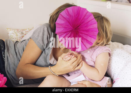 Mother and daughter hiding behind tissue paper flower Stock Photo