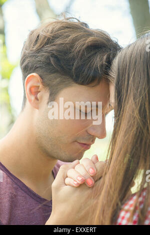 Couple touching foreheads and holding hands outdoors Stock Photo