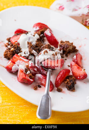 Chocolate muffins with nuts and cherry, strawberries on side, white plate, selective focus Stock Photo