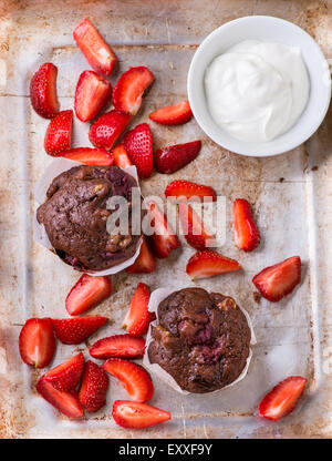 Chocolate muffins with nuts and cherry, metal background, strawberries on side, selective focus Stock Photo