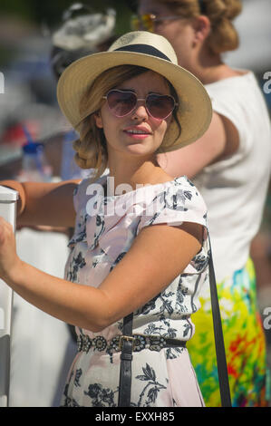 Female spectator in summer dress hat and sunglasses Stock Photo