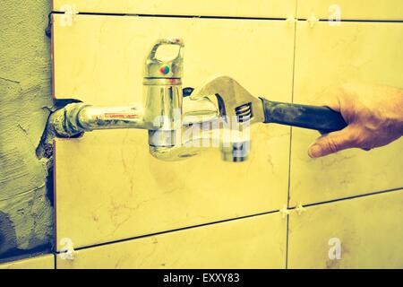 Vintage photo of plumbers hands tightening a water pipe. Authentic and accurate content depiction. Stock Photo