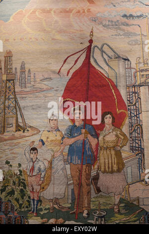 An old rug depicting oil rigs and Azerbaijani family holding the Soviet flag displayed at the Azerbaijan Carpet Museum in the city of Baku capital of Azerbaijan Stock Photo