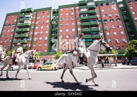 Horse rider's dressed in traditional Seville dress pass modern apartments in centre of Seville, Andalucia, Spain, Europe. Photo Stock Photo