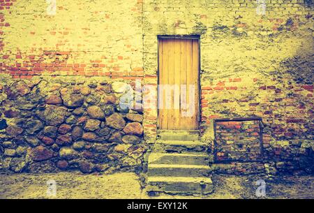 Vintage photo of wall of old abandoned building with wooden doors Stock Photo