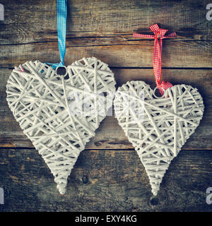 Two wicker hearts hanging on old wooden wall.