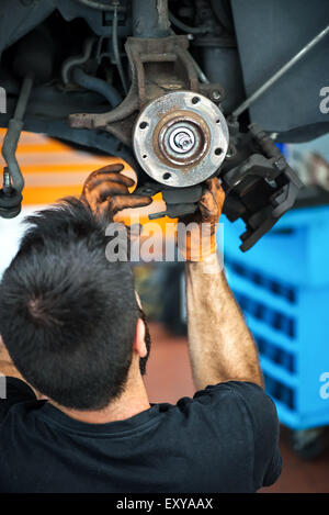 High angle view from behind his head of the hands of a mechanic working on car brakes Stock Photo