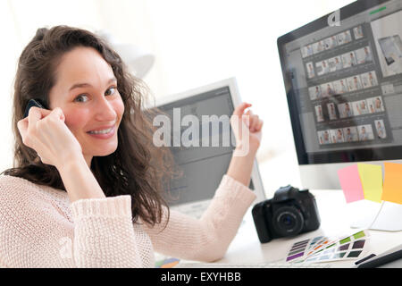 View of Young woman photographer calling customer after a shooting Stock Photo