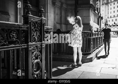 UK lifestyle: Woman person smoking a cigarette outside an office building, Leeds Stock Photo