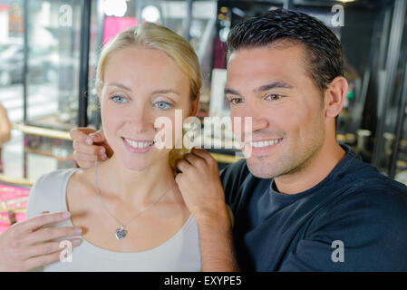 Man trying heart shaped necklace on girlfriend Stock Photo