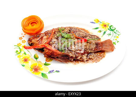 Thai fried fish and cooked on a plate with peppers and the peel of an orange Stock Photo