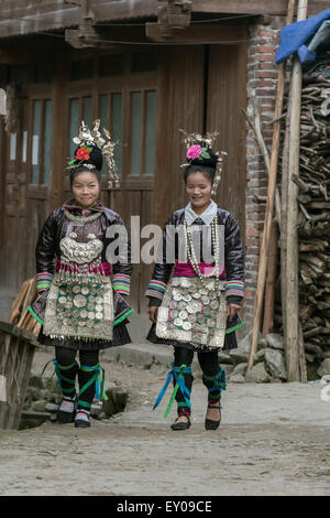 Dong women in traditional attire walking in the village, Huanggang Dong Village, Guizhou Province, China Stock Photo