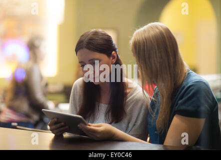 Two women in the restaurant using electronic tablet Stock Photo
