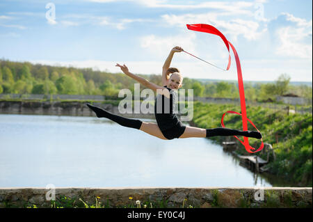 Gymnast girl doing leg-split in a jump with ribbon Stock Photo