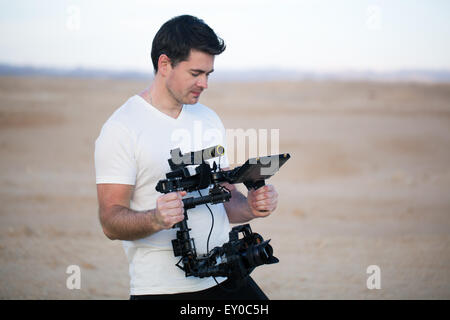 Young man using steadycam for shooting on beach Stock Photo