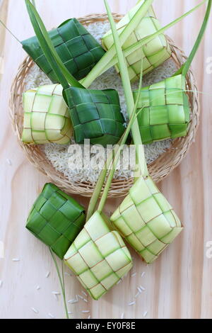 Freshly woven ketupat casings on wooden board Stock Photo