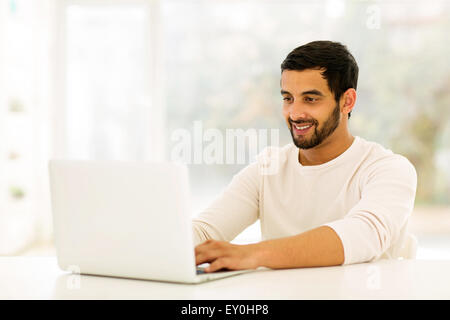 smiling young Indian man using laptop at home Stock Photo