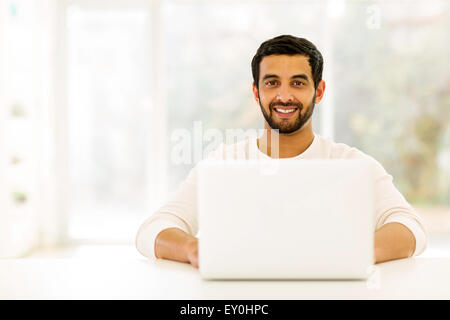 happy young Indian man relaxing at home with laptop Stock Photo