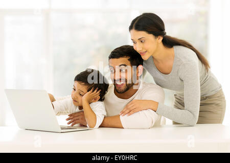 adorable young Indian family using laptop at home Stock Photo