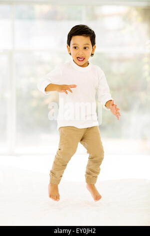 playful little Indian boy jumping on bed at home Stock Photo