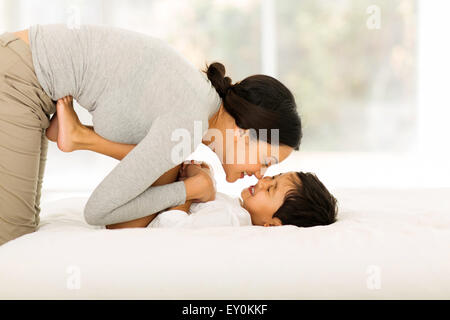 happy Indian mother playing with her little boy on bed Stock Photo