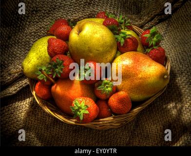 Pears and strawberries in a wicker basket on hessian. Stock Photo