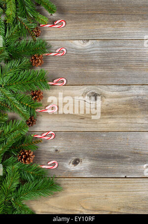 Christmas border with pine tree branches, and candy canes on rustic wooden boards. Layout in vertical format. Stock Photo