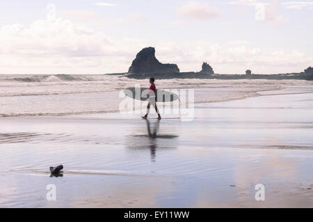 Surfer getting into the water with Morgan's Rock on the background at Playa Maderas, Nicaragua Stock Photo