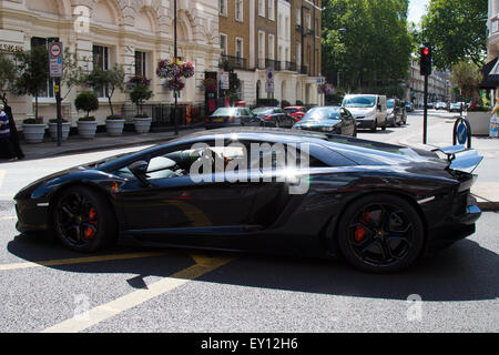 Edgeware Road, London, UK. 19th July, 2015. The driver of a 750 hp Lamborghini engages in a text conversation whilst in charge of his 217mph hypercar in London's Edgeware Road, seemingly unaware of the dangers of not properly concentrating whilst in chage of such an immesely pwerful vehicle in such a busy area. Credit:  Paul Davey/Alamy Live News Stock Photo