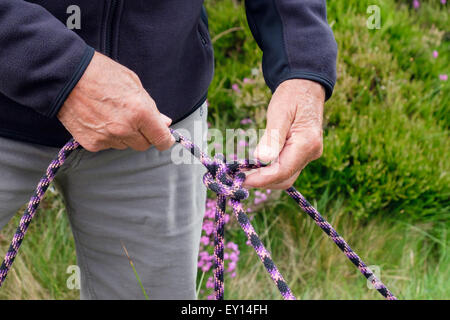 Rock climber demonstrating tying a double bowline knot in a climbing belay rope. Wales, UK, Britain Stock Photo