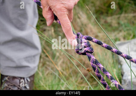 Rock climber demonstrating tying a double bowline knot in a climbing belay rope. UK, Britain Stock Photo